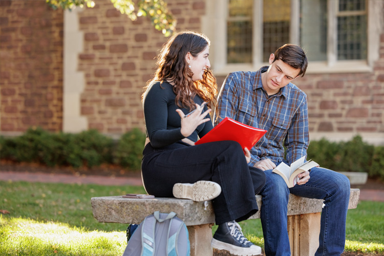 students talking on bench outside